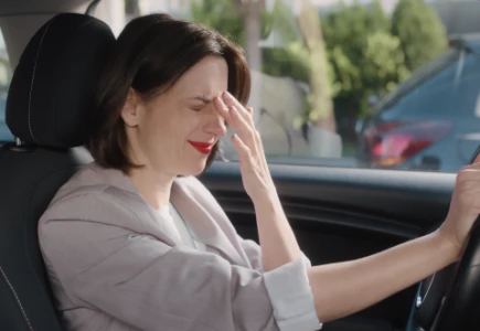  Eine überfordert wirkende Frau sitzt auf dem Fahrersitz im Auto.